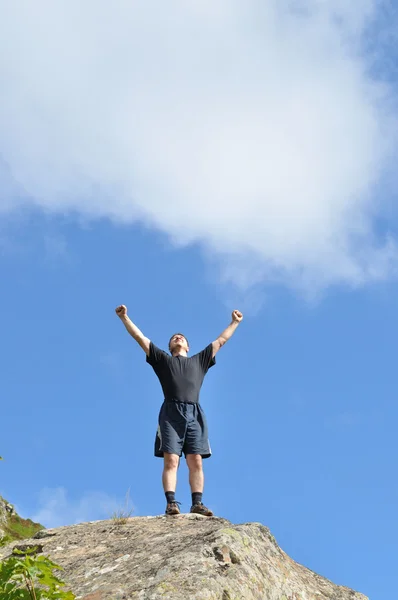 A young man stands on a cliff top and raised his hands to the top expresses — Stock Photo, Image