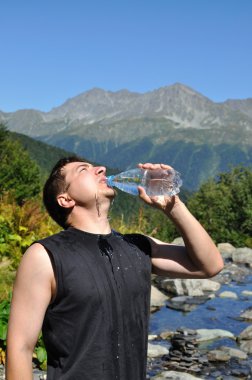 The young man eagerly drinking water from plastic bottles clipart