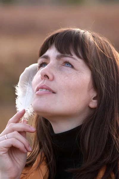 Girl with a bird feather — Stock Photo, Image