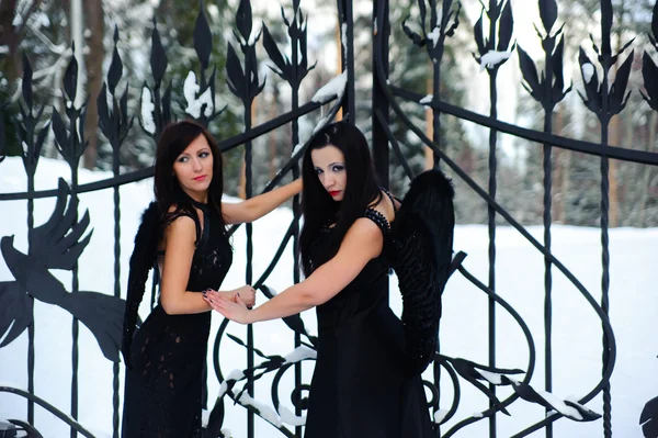 Two girls in black dresses against a snow-covered landscape — Stock Photo, Image