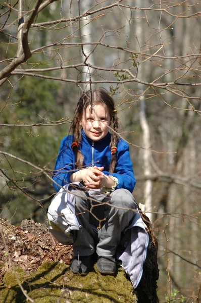 Dívka, sedící na starý strom v pole — Stock fotografie