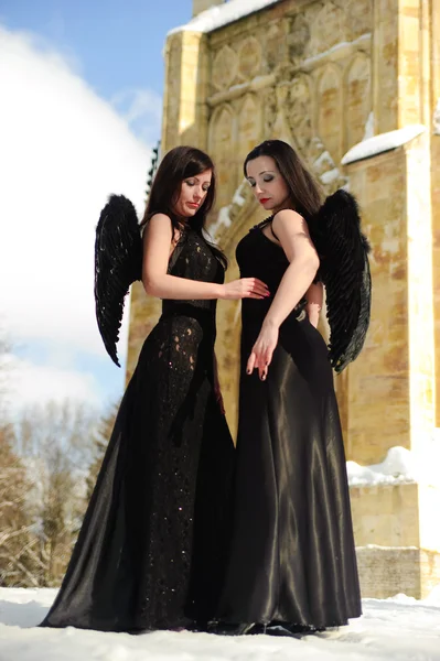 Två tjejer i svarta klänningar mot ett snötäckt landskap — Stockfoto