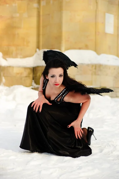 Het meisje in een zwarte jurk met zwarte vleugels — Stockfoto