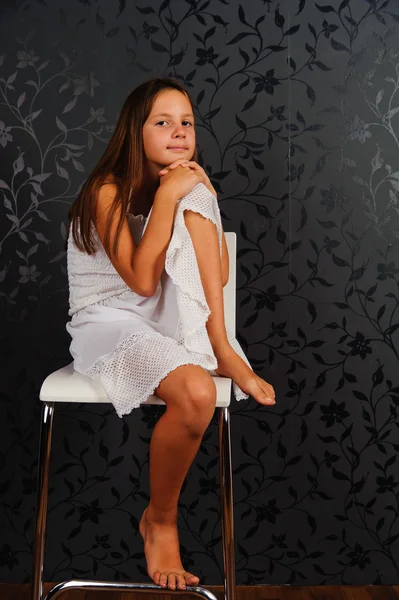 A menina de roupas brancas sentada em uma cadeira — Fotografia de Stock