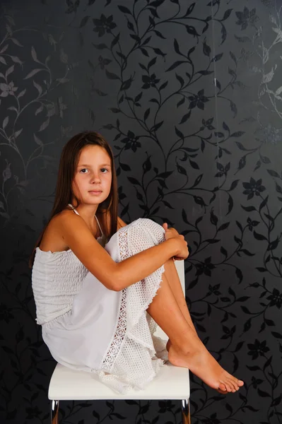 Het meisje in witte kleren, zittend op een stoel — Stockfoto