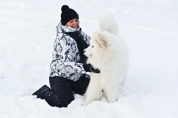 Nainen Jolla Valkoinen Koira Lumessa — kuvapankkivalokuva
