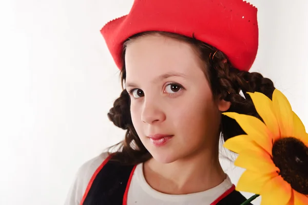 Dziewczyna w czerwonym kapeluszu z słoneczników w rękami — Zdjęcie stockowe