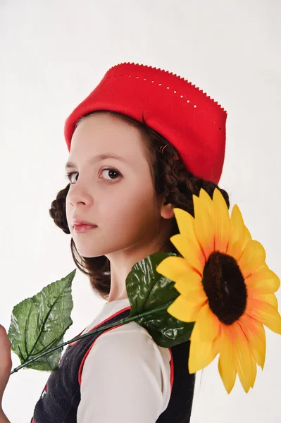 Jente med rød hatt med solsikker i hendene – stockfoto