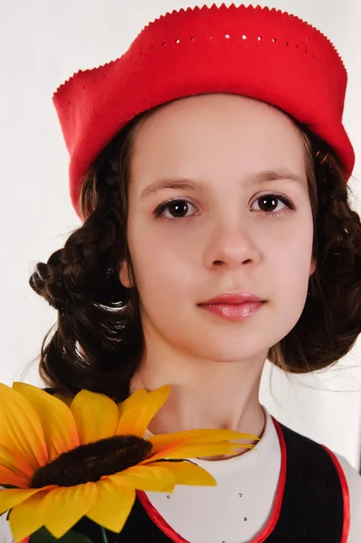 Dívka v červeném klobouku s slunečnice v jejich rukou — Stock fotografie