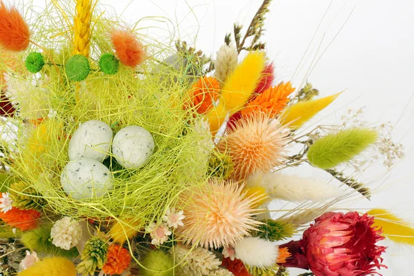 stock image Three cute little quail eggs on colorful dry flowers - Easter decoration background