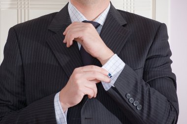 A man buttoning his light blue shirt. clipart