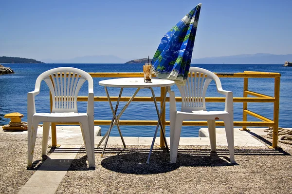 Sommige stoelen en een tafel op de haven van skiathos eiland. Stockfoto