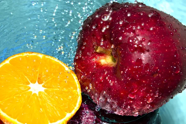 Яблоко и апельсин в капли воды — стоковое фото