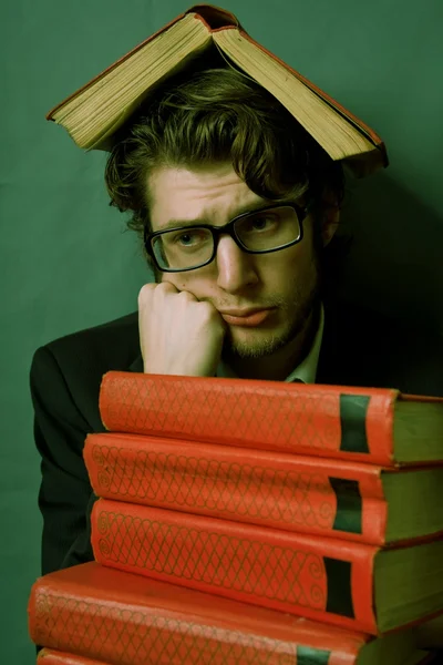 Triste jeune homme avec une pile de livres rouges — Photo