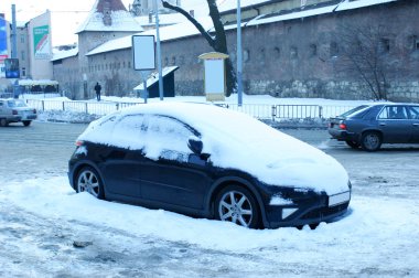 siyah bir araba karda cadde şehir içinde sıkışmış.