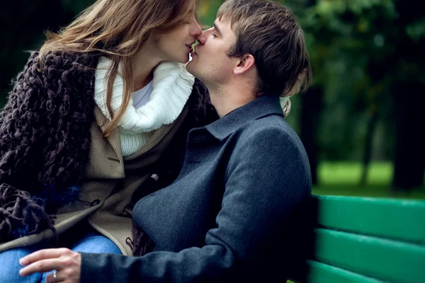 stock image A young lovely couple kissing on a bench in the park