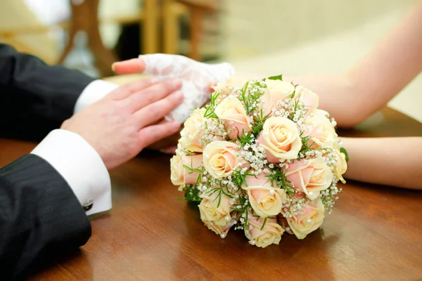 Handen met ringen en bruiloft boeket — Stockfoto