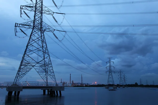 Strommasten auf See passieren petrochemische Industrieanlagen — Stockfoto