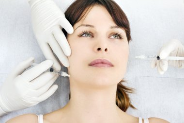 Young caucasian woman receiving an injection of botox from a doctor clipart