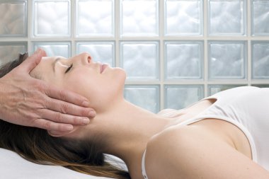 Young caucasian woman lying down receiving head massage clipart
