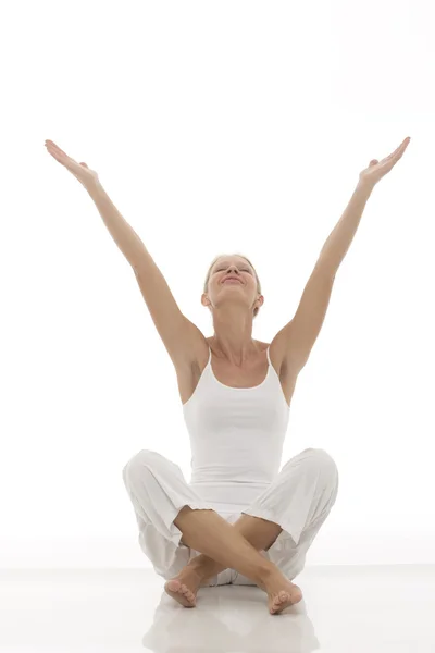 Una joven caucásica vestida de blanco sentada con las piernas cruzadas haciendo yoga —  Fotos de Stock