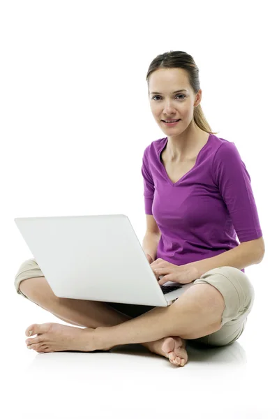 Jovem mulher sentada no chão com laptop no estúdio de fundo branco — Fotografia de Stock