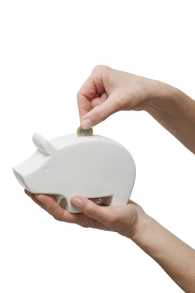 Hand één munt aanbrengend een piggy bank — Stockfoto