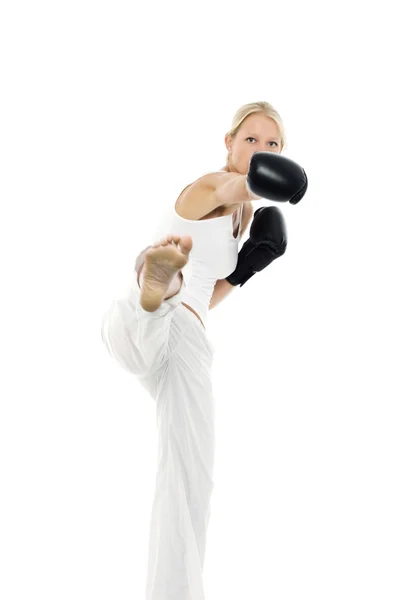 Portrait d'une jeune femme caucasienne qui donne un coup de pied de boxe avec des gants de boxe — Photo