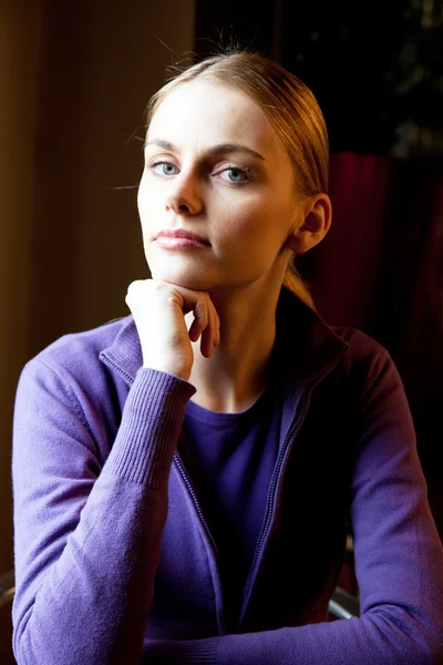 Portrait of young woman with hand under chin looking at camera — Stock Photo, Image
