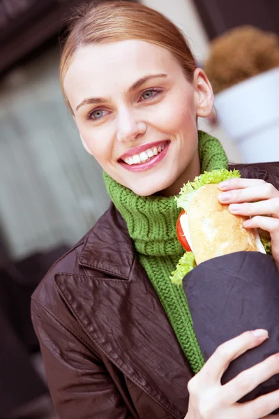 Young smiling woman holding a sandwich — Stock Photo, Image
