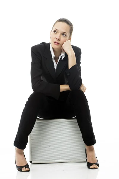 Young businesswoman sitting on a briefcase on white background studio — Stock Photo, Image