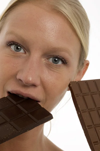 Young beautiful caucasian woman eating a chocolate bar and looking at the c — Stock Photo, Image