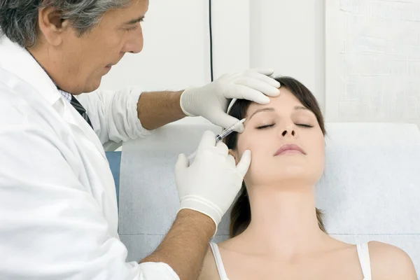 Junge kaukasische Frau erhält von einem Arzt eine Botox-Injektion — Stockfoto