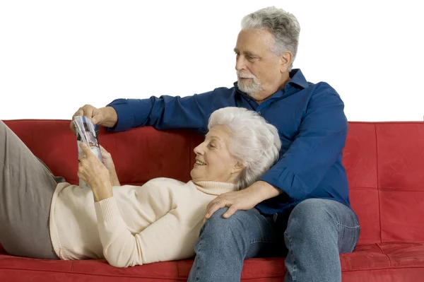 Couple âgé sur le canapé lisant un magazine — Photo