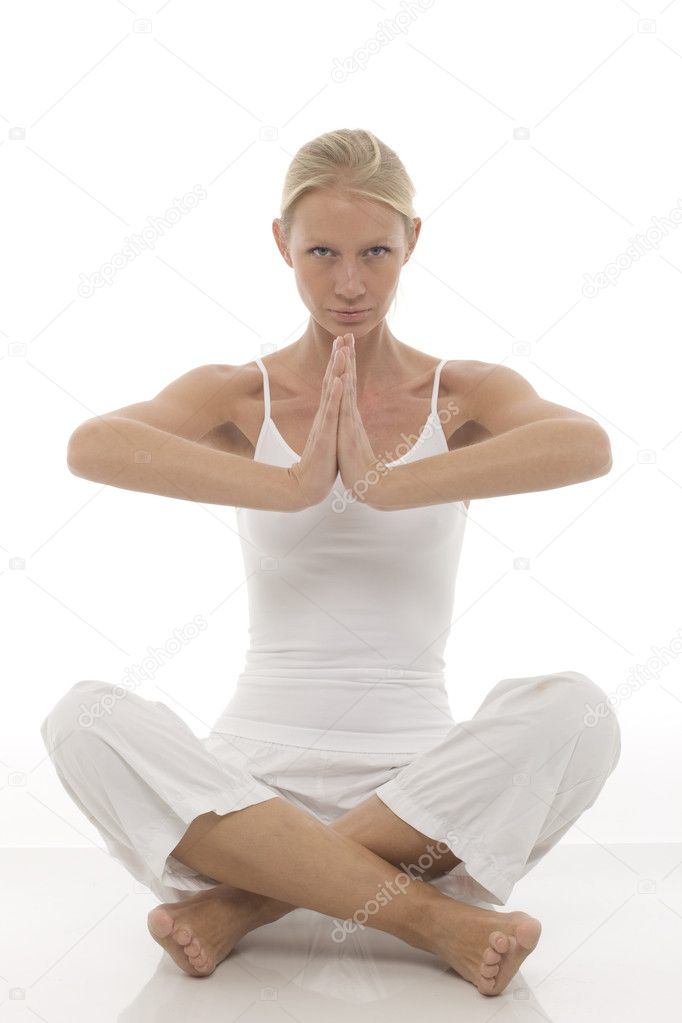 A young caucasian woman dressed in white sitting cross-legged doing yoga