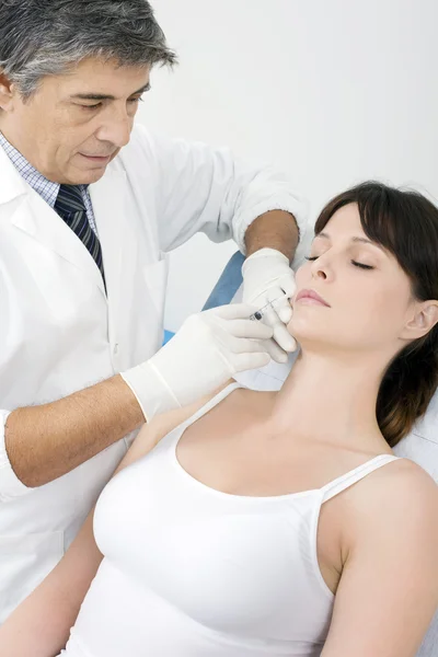 Mulher caucasiana jovem a receber uma injeção de botox de um médico — Fotografia de Stock