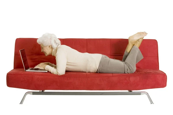 Пожилая женщина на диване с ноутбуком — стоковое фото
