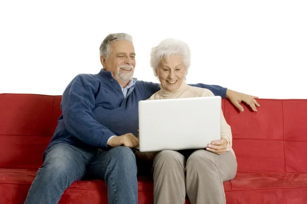 Пожилая пара на диване с ноутбуком — стоковое фото