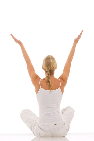 Mulher vestida de branco sentado de pernas cruzadas fazendo ioga — Fotografia de Stock
