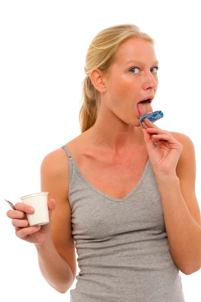 Portrait of a young caucasian woman who licks the lid of a pot of yogurt — Stock Photo, Image