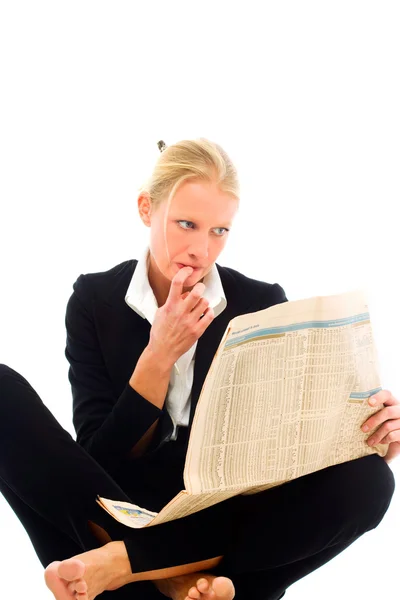 Woman wearing a black jacket sitting down and reading a newspaper looking f — Stock Photo, Image