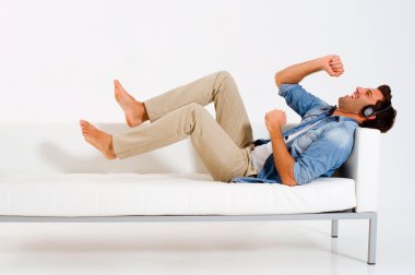 Man on the couch listening music clipart