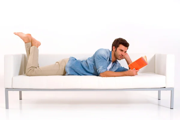Homme sur le canapé lisant un livre — Photo