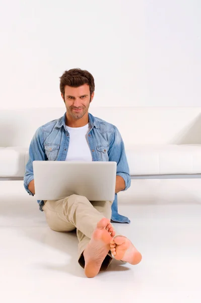 ノートパソコンを持って床に座る男は — ストック写真