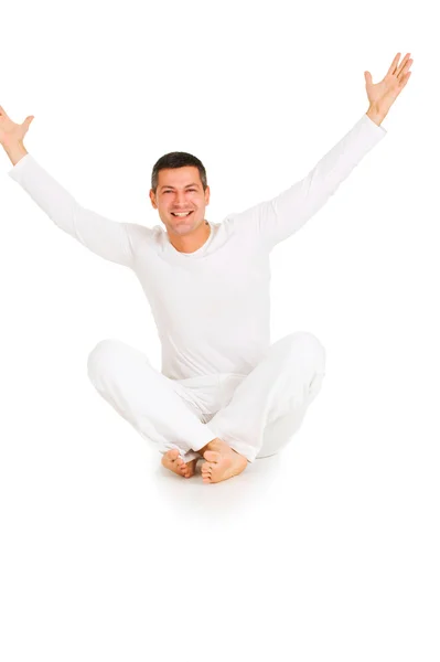 Uomo vestito di bianco seduto sul pavimento con le braccia alzate — Foto Stock
