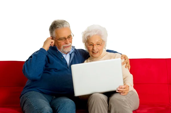 Yaşlı çift kanepede bir dizüstü bilgisayar kullanarak — Stok fotoğraf