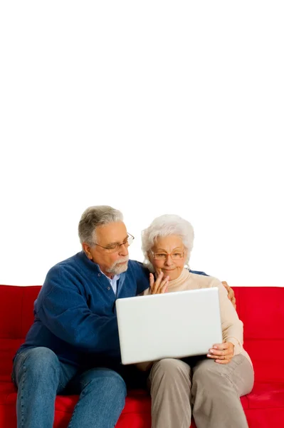 Пожилая пара на диване с ноутбуком — стоковое фото