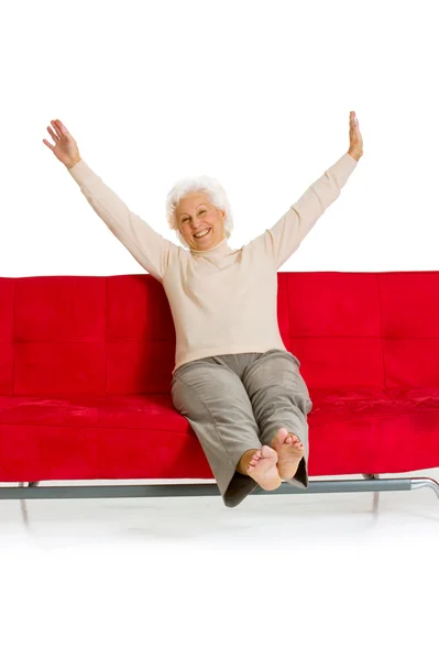 Starší žena uvolňující na gauči — Stock fotografie
