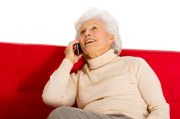 Donna anziana sul divano con cellulare — Foto Stock
