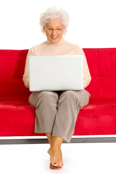 Äldre kvinna i soffan med laptop — Stockfoto
